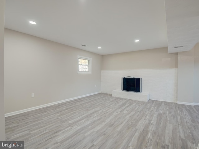 basement featuring light hardwood / wood-style floors and a fireplace