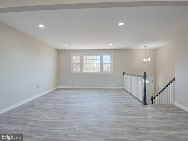 unfurnished room with light wood-type flooring and an inviting chandelier