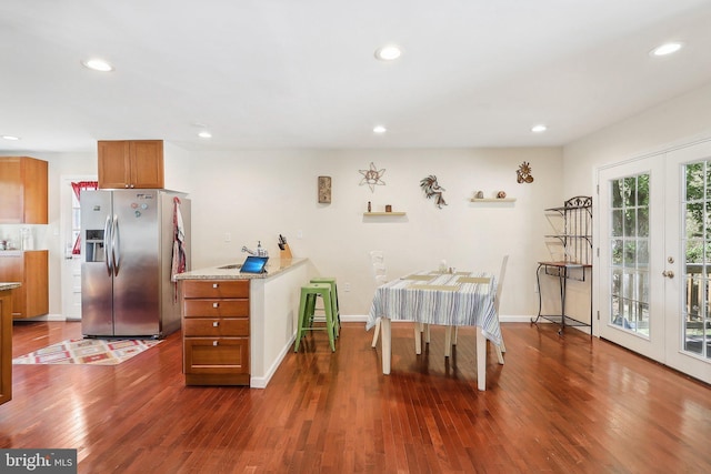 kitchen featuring light stone countertops, stainless steel fridge, french doors, and dark hardwood / wood-style floors