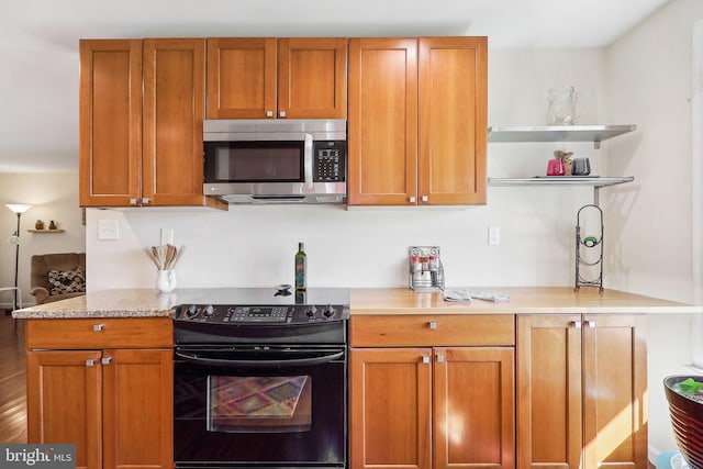 kitchen featuring black electric range oven and light stone counters