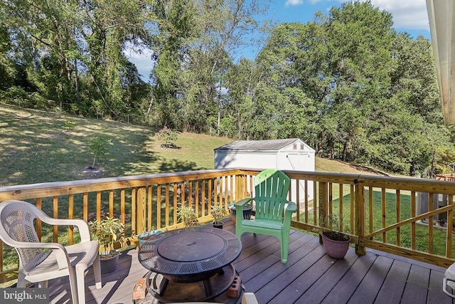 wooden deck with a storage unit, a yard, and an outdoor fire pit