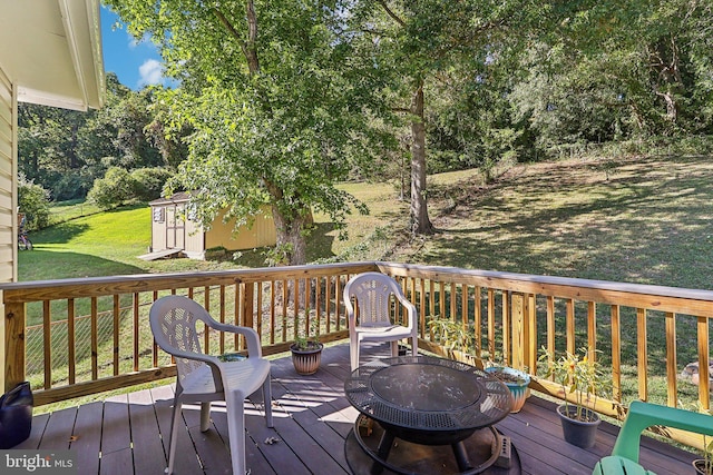 deck featuring a fire pit, a yard, and a shed