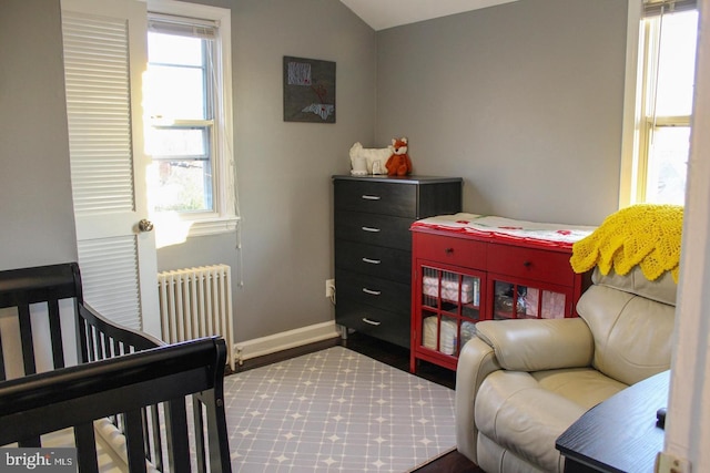 bedroom featuring multiple windows, radiator heating unit, a nursery area, and lofted ceiling