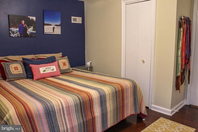 bedroom with dark hardwood / wood-style floors and a closet