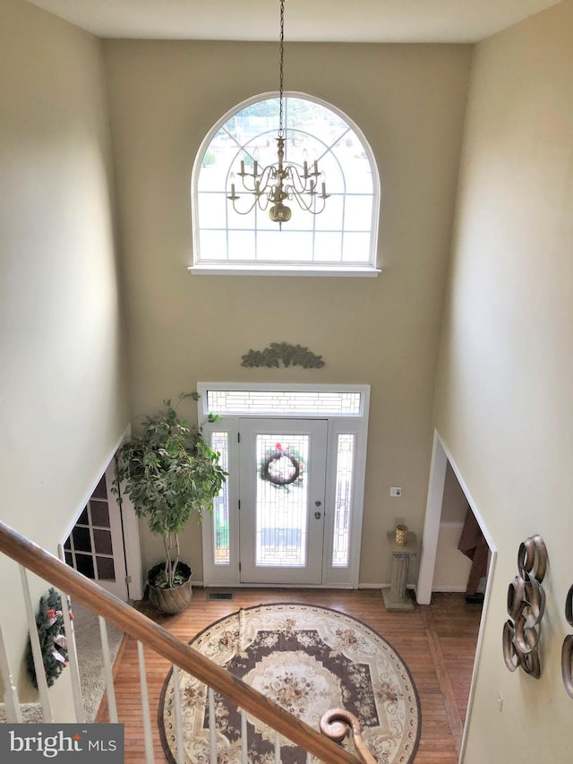 foyer with a chandelier, hardwood / wood-style floors, and a towering ceiling