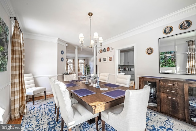 dining area with light hardwood / wood-style floors, an inviting chandelier, ornamental molding, and ornate columns