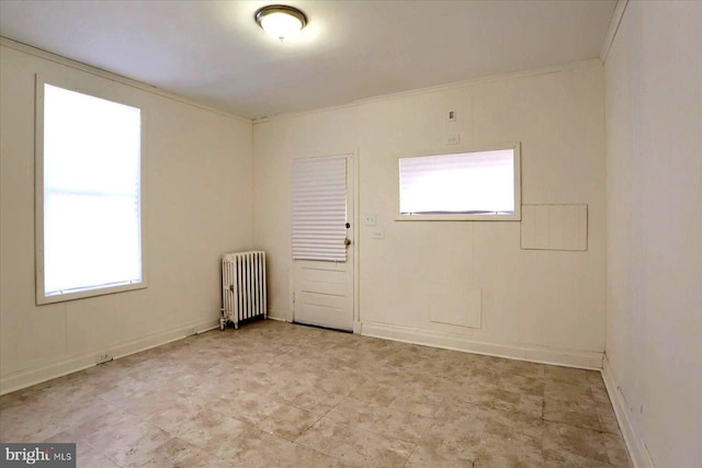 spare room with crown molding and radiator