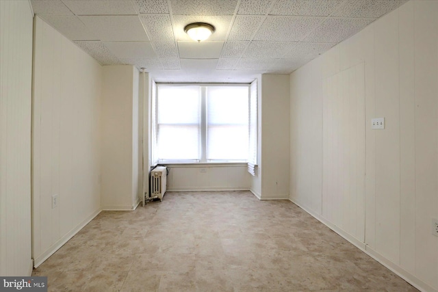 spare room with radiator and a paneled ceiling