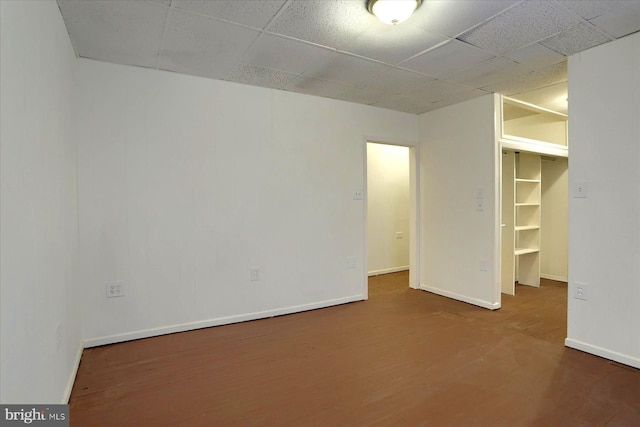 unfurnished bedroom with a spacious closet, hardwood / wood-style flooring, and a drop ceiling