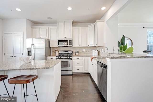 kitchen with white cabinetry, kitchen peninsula, sink, and appliances with stainless steel finishes