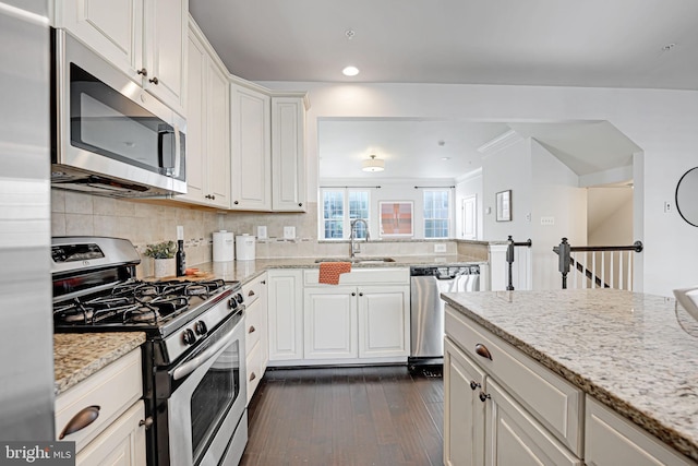 kitchen with dark wood-type flooring, white cabinets, sink, light stone counters, and stainless steel appliances