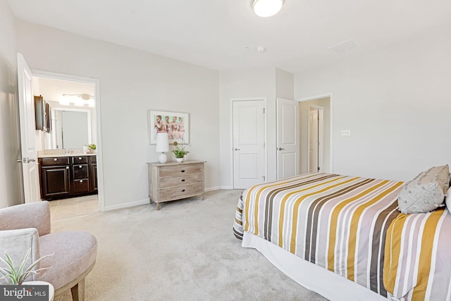 bedroom featuring ensuite bathroom and light carpet