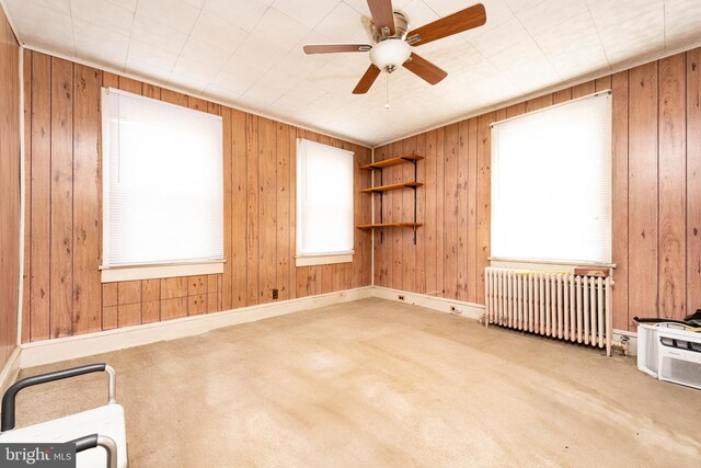 unfurnished room with carpet flooring, ceiling fan, and radiator heating unit