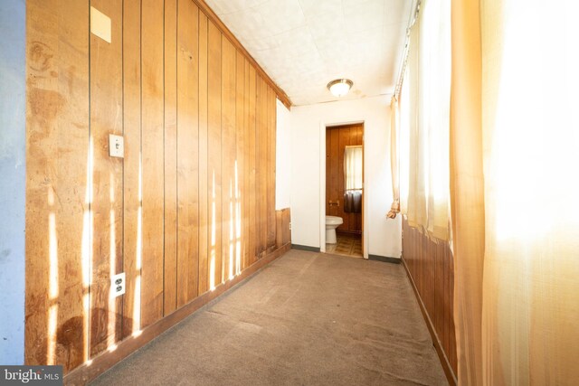 corridor with carpet and wood walls