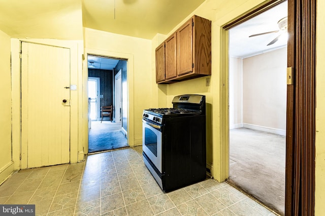 kitchen featuring black gas range, light colored carpet, and ceiling fan