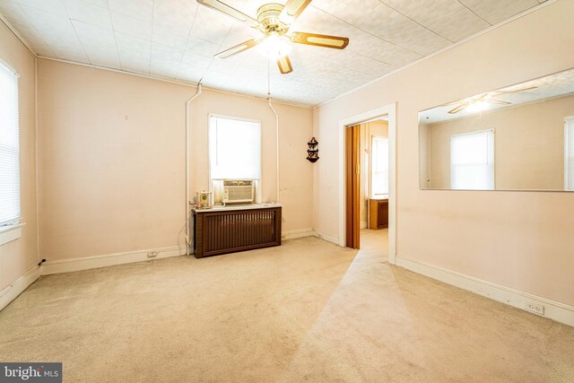 carpeted empty room featuring plenty of natural light, radiator, cooling unit, and ceiling fan