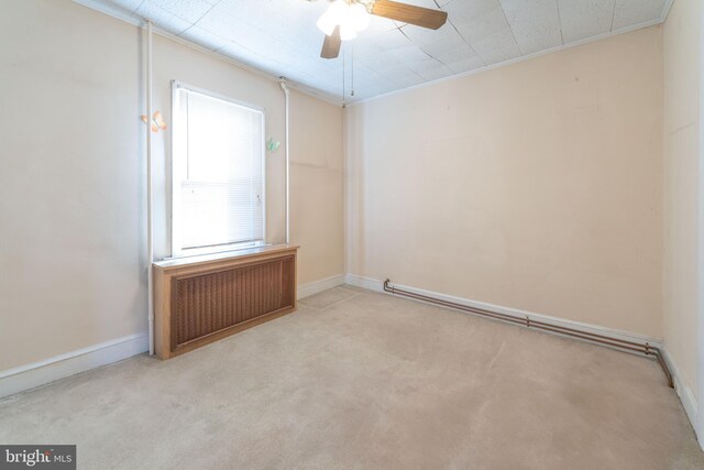 spare room with ceiling fan, crown molding, radiator heating unit, and light carpet