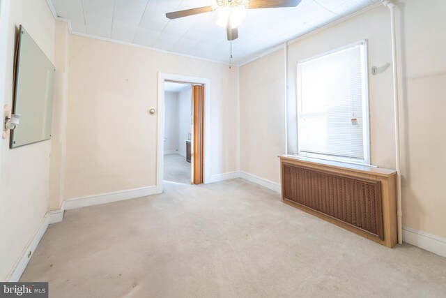 carpeted spare room featuring radiator, ornamental molding, and ceiling fan