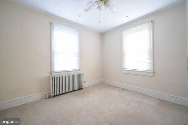 spare room with light carpet, radiator heating unit, and ceiling fan