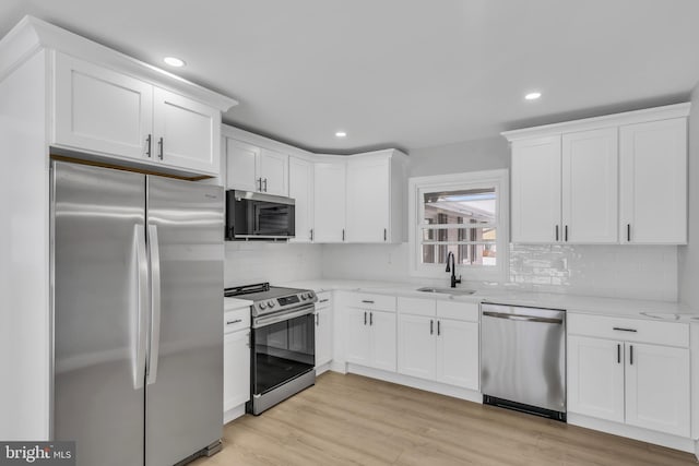 kitchen featuring white cabinetry, sink, stainless steel appliances, and light wood-type flooring