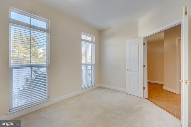 unfurnished room featuring light colored carpet and a healthy amount of sunlight