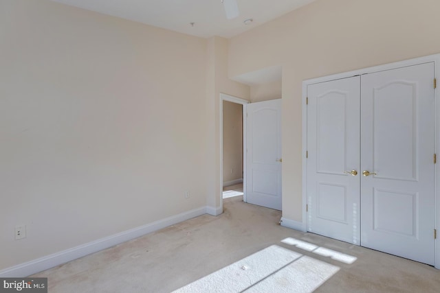 unfurnished bedroom featuring ceiling fan, light colored carpet, and a closet