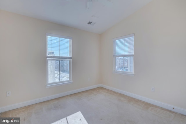 spare room with light carpet, a wealth of natural light, and lofted ceiling