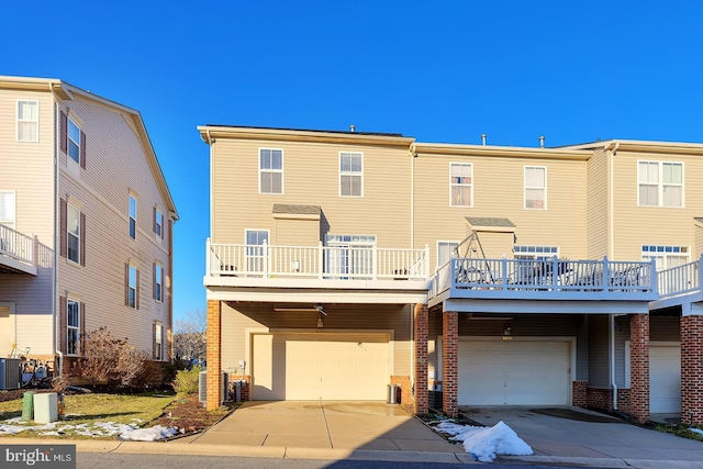 rear view of house with central AC unit, a garage, and a balcony