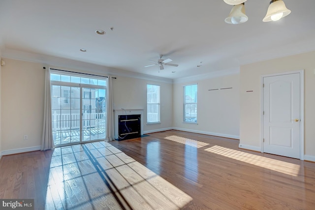 unfurnished living room featuring crown molding, ceiling fan with notable chandelier, and hardwood / wood-style floors