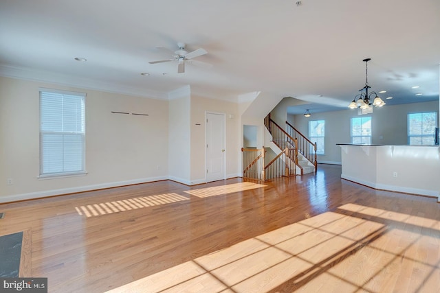 unfurnished living room featuring crown molding, ceiling fan with notable chandelier, and light hardwood / wood-style floors