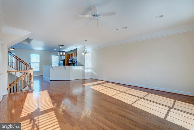 unfurnished living room with light hardwood / wood-style floors, crown molding, and ceiling fan with notable chandelier