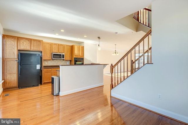 kitchen featuring an inviting chandelier, tasteful backsplash, light wood-type flooring, hanging light fixtures, and black appliances