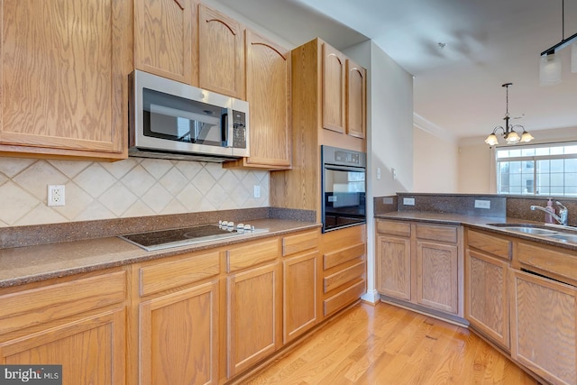 kitchen featuring light wood-type flooring, black oven, sink, a notable chandelier, and electric cooktop