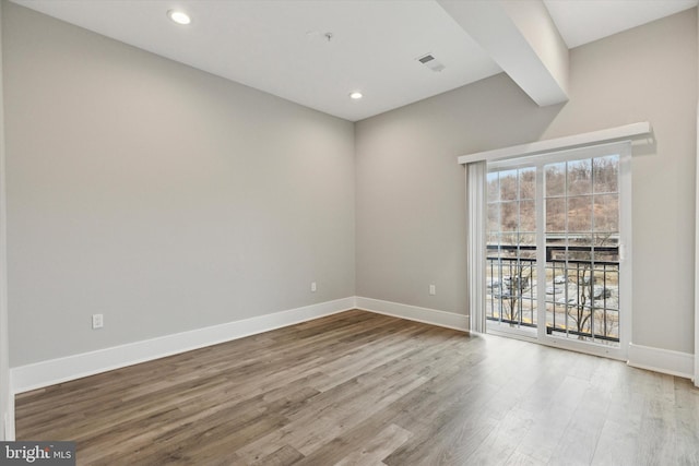 empty room featuring visible vents, baseboards, wood finished floors, and recessed lighting