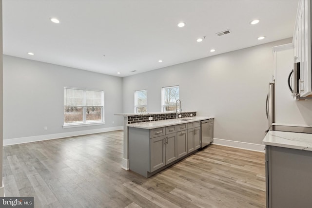 kitchen with stainless steel appliances, light wood-type flooring, a peninsula, and gray cabinetry