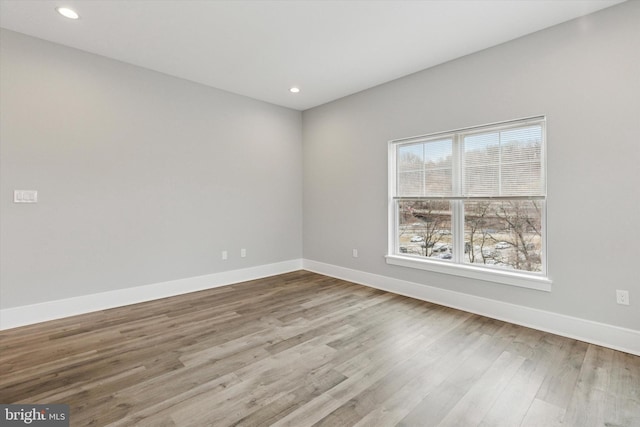 spare room featuring recessed lighting, wood finished floors, and baseboards