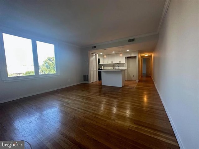 unfurnished living room with ornamental molding and dark wood-type flooring