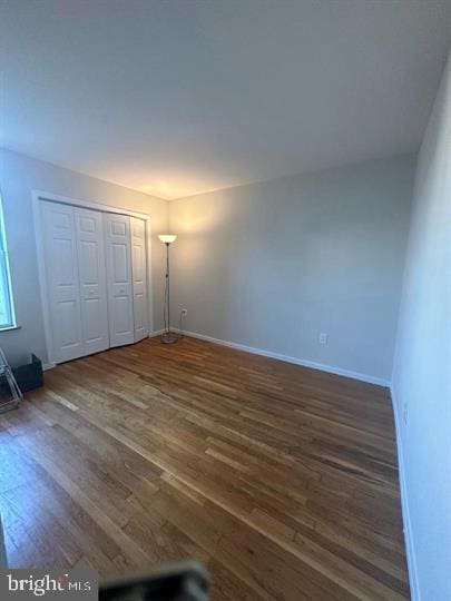 unfurnished bedroom featuring dark wood-type flooring and a closet