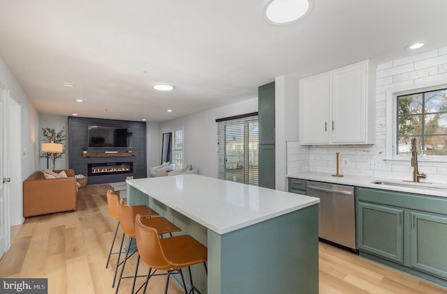 kitchen with white cabinets, a fireplace, sink, dishwasher, and a center island