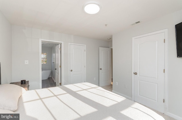 bedroom featuring ensuite bathroom and carpet floors