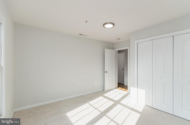 unfurnished bedroom featuring light colored carpet and a closet