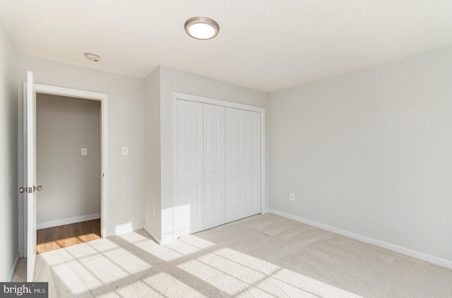 unfurnished bedroom featuring a closet and light colored carpet