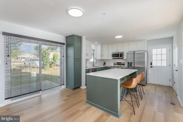 kitchen featuring sink, stainless steel appliances, a kitchen island, a kitchen breakfast bar, and white cabinets