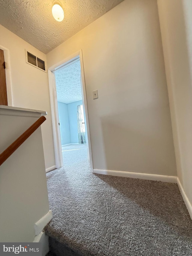 hallway featuring carpet floors and a textured ceiling