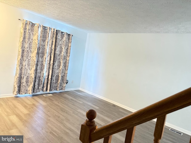 empty room featuring wood-type flooring and a textured ceiling