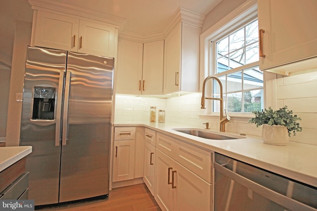 kitchen featuring appliances with stainless steel finishes, decorative backsplash, hardwood / wood-style flooring, white cabinets, and sink