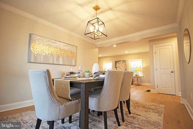 dining room with a notable chandelier, light hardwood / wood-style floors, and ornamental molding