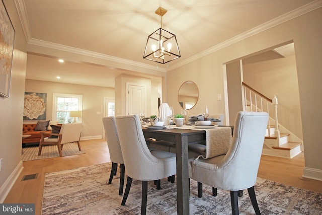 dining area with ornamental molding, a notable chandelier, and light hardwood / wood-style floors