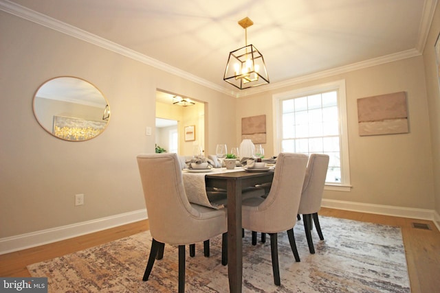 dining room with hardwood / wood-style flooring, a notable chandelier, and crown molding