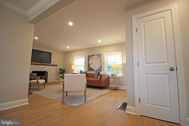 living room with a fireplace, light wood-type flooring, and ornamental molding